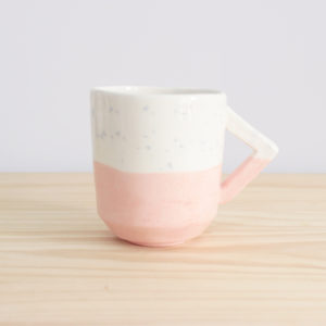 Taza realizada a mano con diseño de asa rectangular en loza blanca en tonos rosas y azules