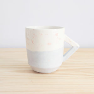 Taza de diseño realizada artesanalmente en loza blanca con decoración en rosa y azul y detalle de asa rectangular