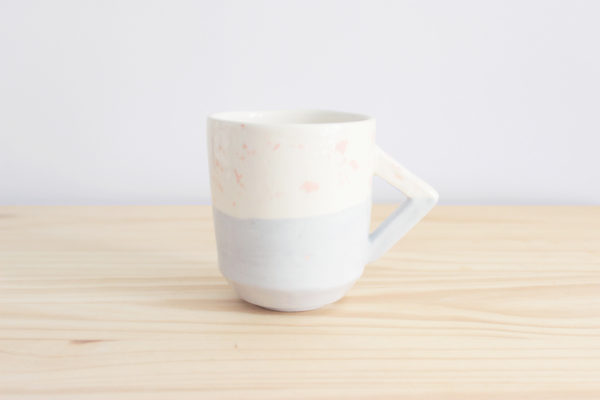 Taza de diseño realizada artesanalmente en loza blanca con decoración en rosa y azul y detalle de asa rectangular